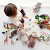 boy sitting on white cloth surrounded by toys