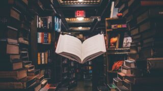 view of floating open book from stacked books in library