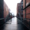 people walking across a bridge in the rain