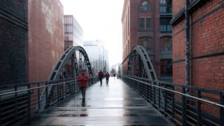 people walking across a bridge in the rain