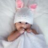 baby in white knit cap lying on white textile