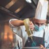 a man in a chef's hat is pouring something into a bowl