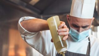 a man in a chef's hat is pouring something into a bowl