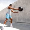 man in white tank top and white shorts holding black ball