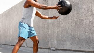 man in white tank top and white shorts holding black ball