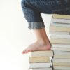 person sitting on stack of books while reading