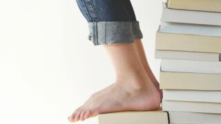 person sitting on stack of books while reading