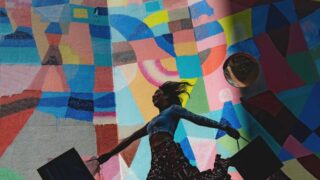 woman holding bag beside mural painting