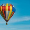 panning photography of flying blue, yellow, and red hot air balloon