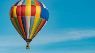 panning photography of flying blue, yellow, and red hot air balloon