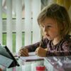 girl in purple and black long sleeve shirt holding black pen writing on white paper