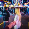 woman wearing white long-sleeved top across ferris wheel during nighttime