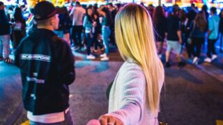 woman wearing white long-sleeved top across ferris wheel during nighttime