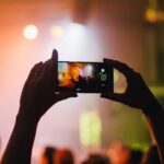 person holding smartphone while taking videos at live concert