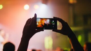 person holding smartphone while taking videos at live concert